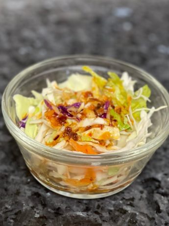 A bowl of coleslaw with chili crisp vinaigrette dressing on it