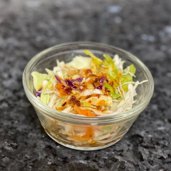 A bowl of coleslaw with chili crisp vinaigrette dressing on it